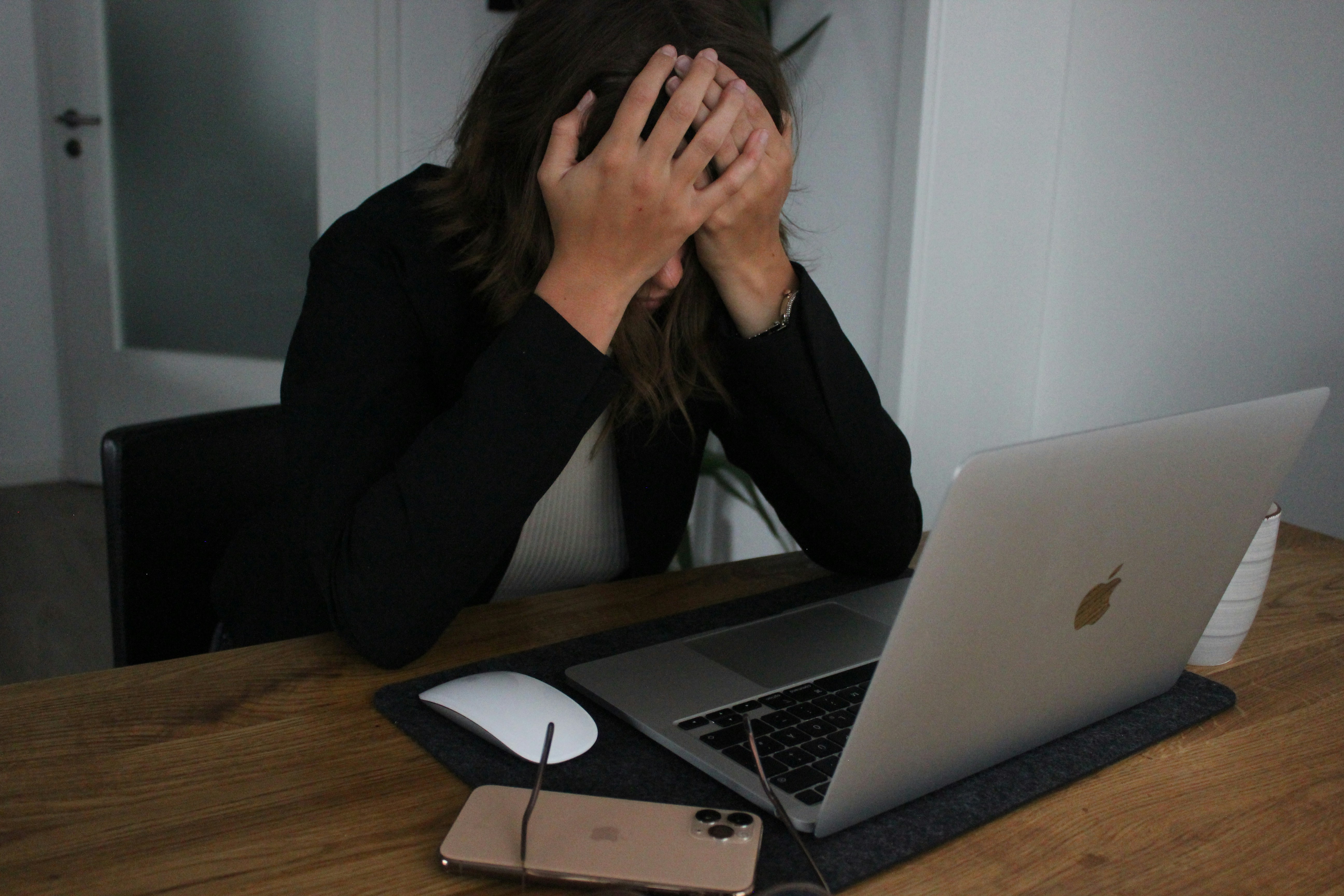a woman covering her face while looking at a laptop